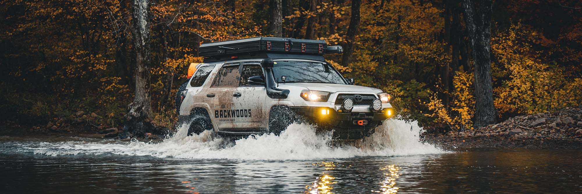 A 5th gen Toyota 4Runner overlanding through a water crossing with Backwoods Adventure Mods products on the vehicle.