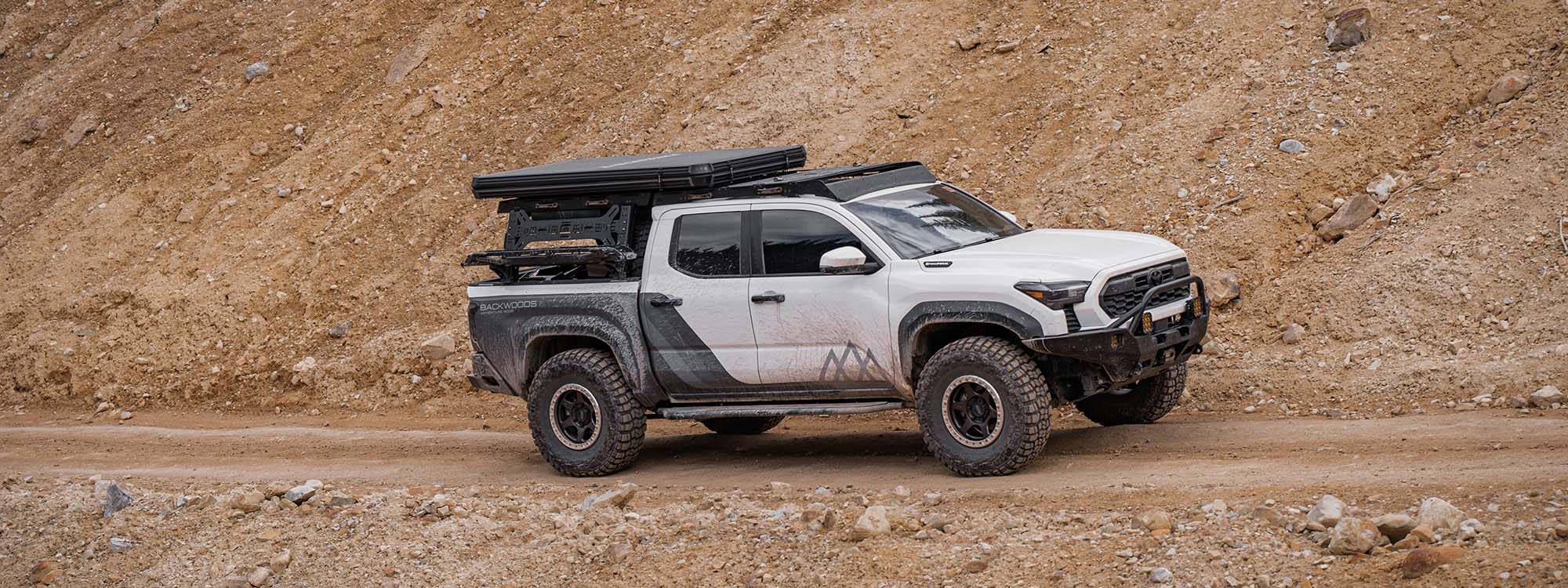 A An offroad and overland 2024 Toyota Tacoma driving on a dirt road