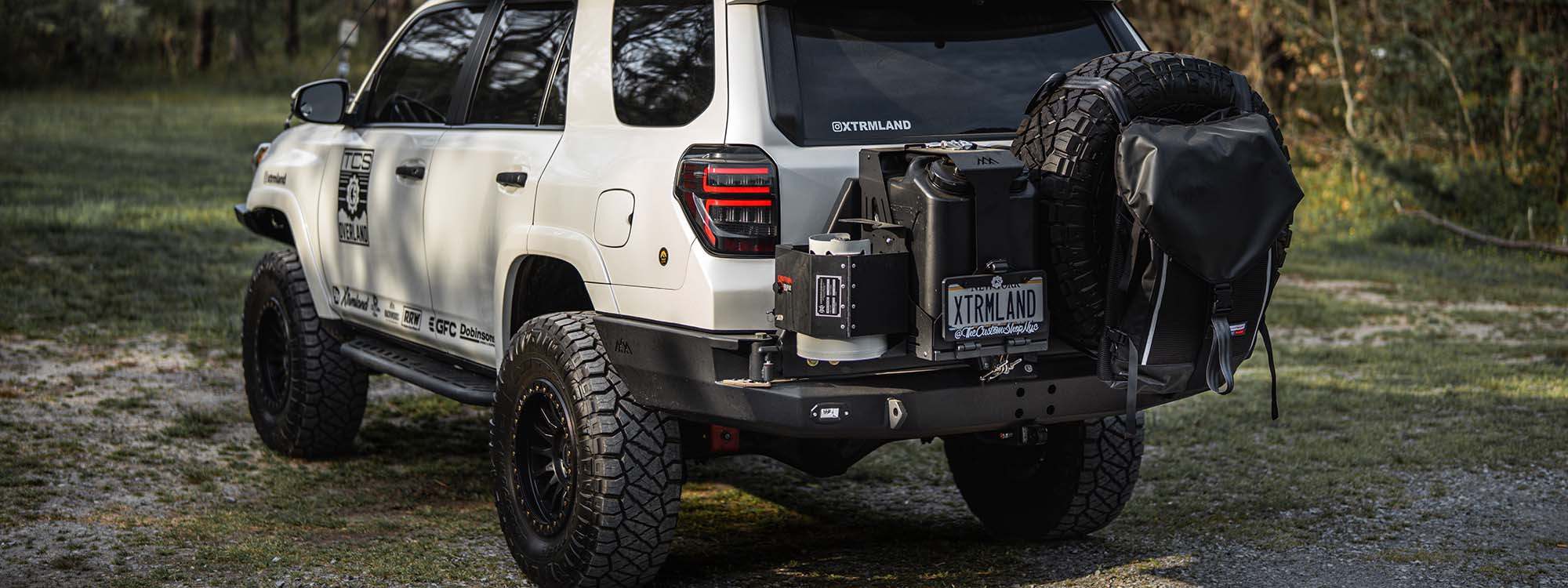 A toyota 4runner built for overlanding and offroading with a backwoods adventure mods dual jerry can holder on the rear bumper.