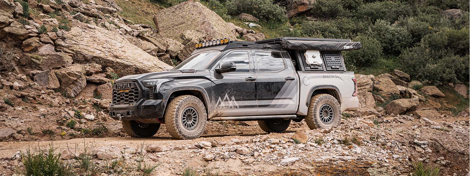 A 2022 Toyota Tundra truck driving on a trail in the colorado mountains with backwoods adventure mods overland gear on it.