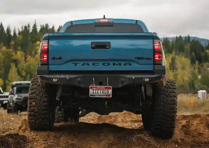 Backwoods Adventure Mods Toyota Tacoma (2016-2023) Hi-Lite High Clearance Rear Bumper installed on a blue 3rd Gen Tacoma being driven through mud off road
