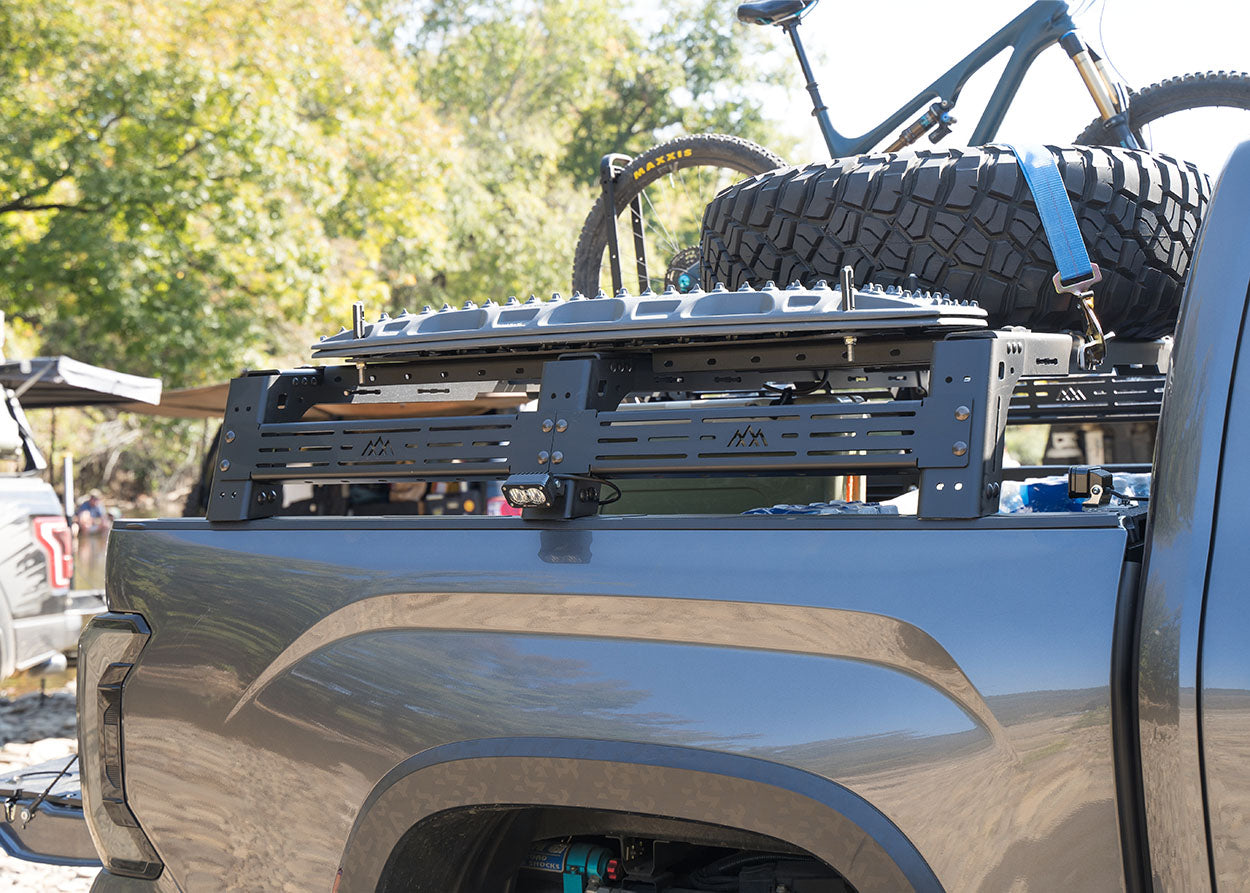 Backwoods Adventure Mods 3rd Gen Toyota Tundra mid-height Bed Rack with off road lights, spare tire, traction boards, and bike rack mounted on top