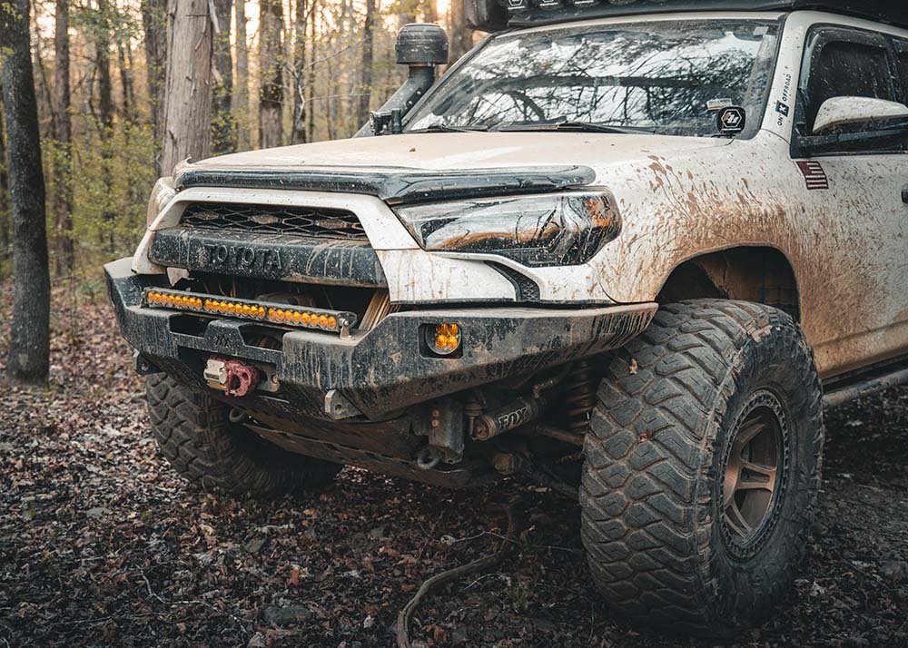Backwoods Adventure Mods 5th Gen Toyota 4Runner Hi-Lite Overland Front Winch Bumper installed on a white 4runner and being used while off roading