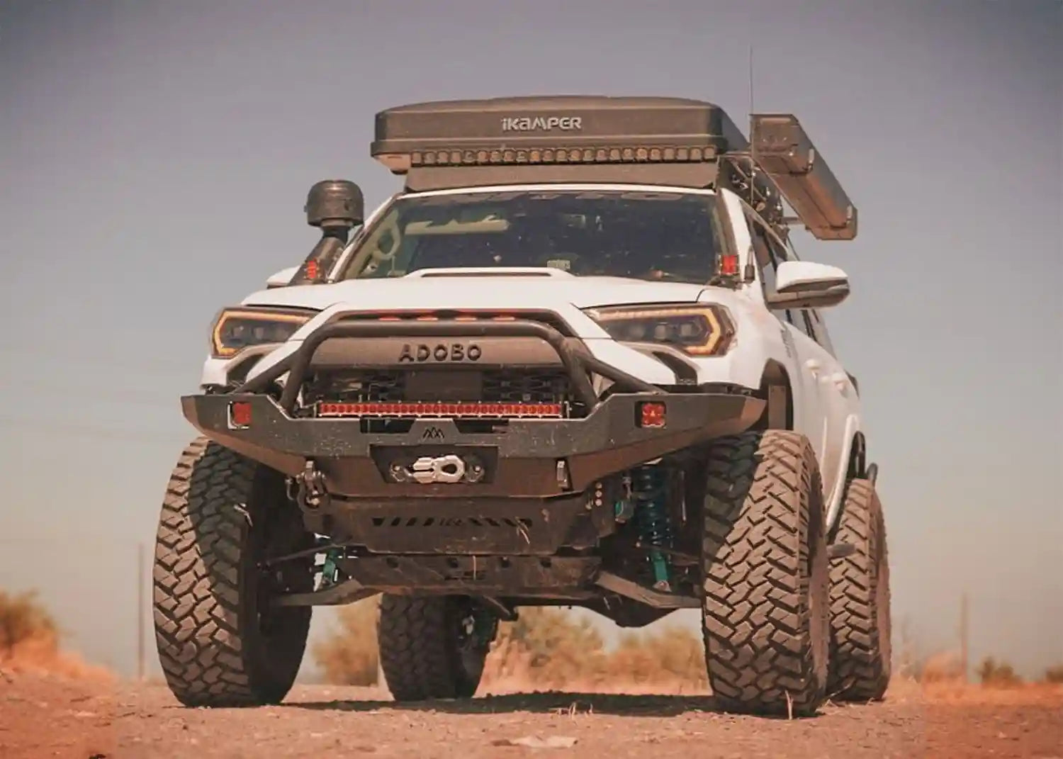 White 5th Gen Toyota 4runner equipped with a Backwoods Adventure Mods Hi-Lite Overland Hybrid Front winch Bumper with Prerunner Bull Bar driving off road