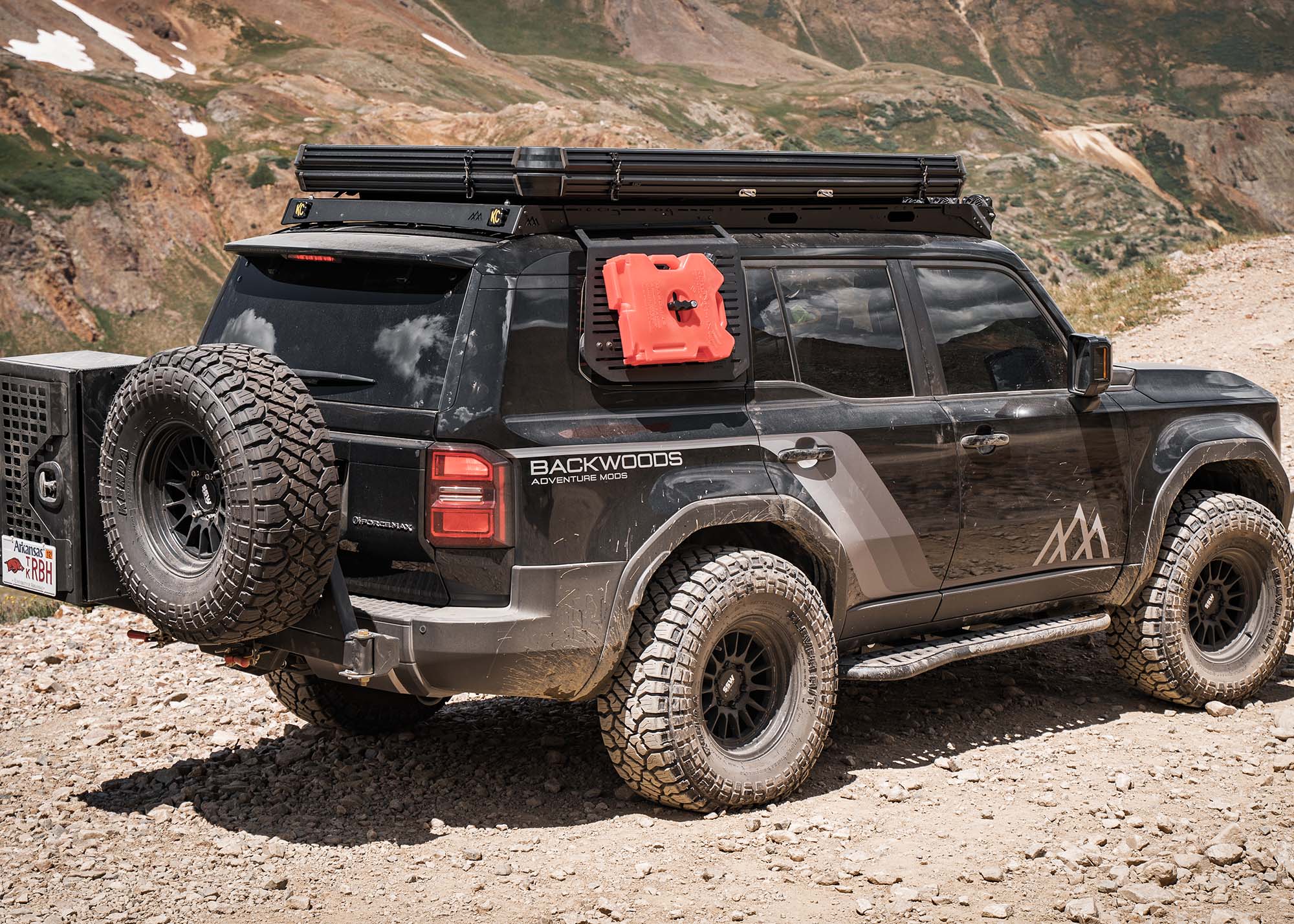 Toyota Land Cruiser 250 driving off road with a Backwoods Adventure Mods DRIFTR roof rack installed and roof top tent mounted on top