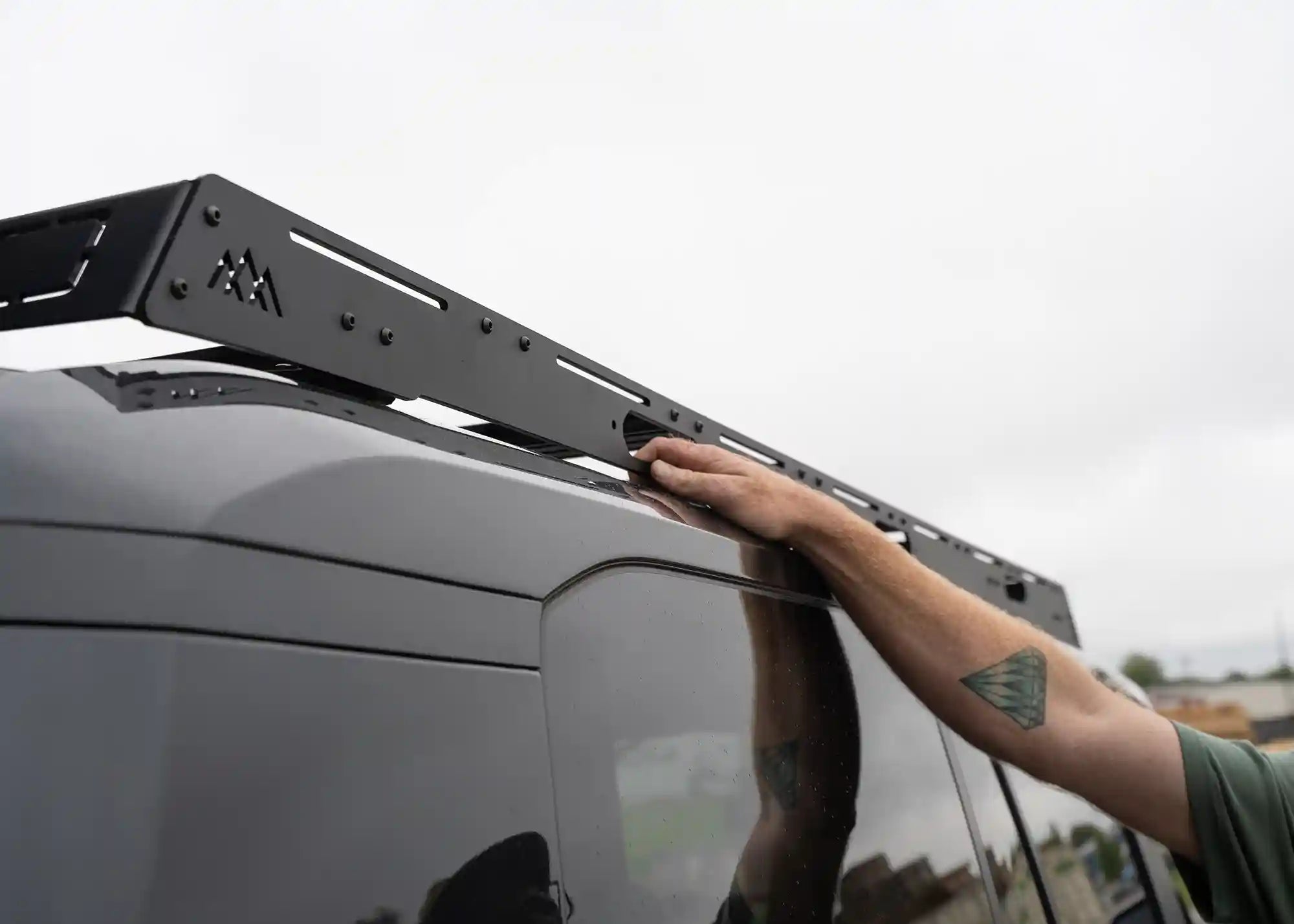 Person using the grab handle on a DRIFTR Lexus GX550 roof rack from Backwoods Adventure Mods to access roof top cargo storage