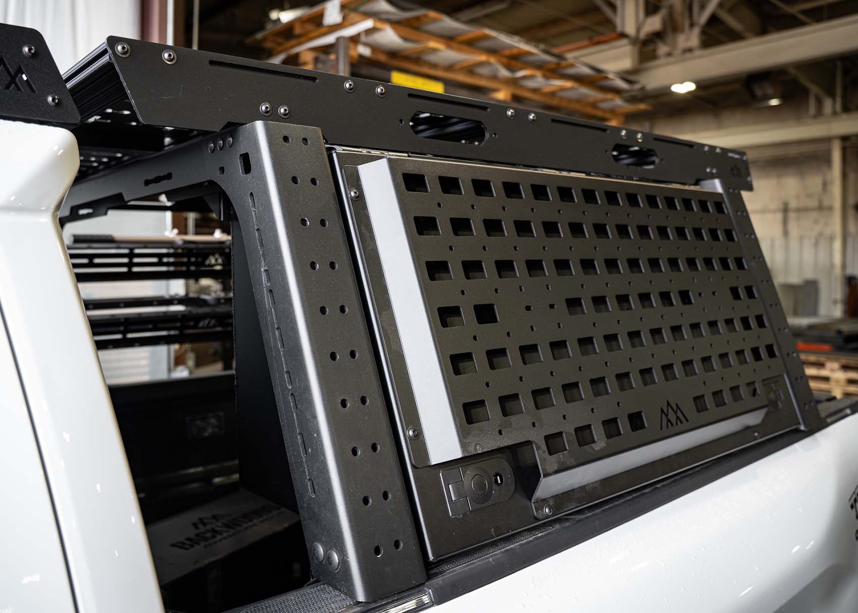 Backwoods Adventure Mods Truck Bed Rack System Overland Enthusiast Bundle installed on a Toyota Tacoma with rack mounted cargo box closed showing molle accessory panel and upper cargo storage deck