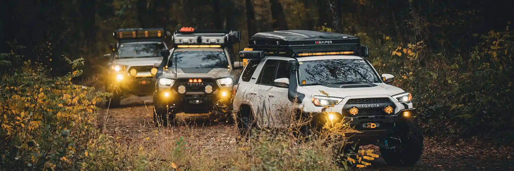Three Toyota overland vehicles equipped with Backwoods Adventure Mods accessories driving off road