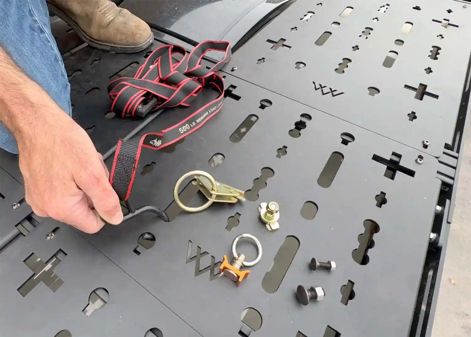 Man demonstrating the various attachments that can be used to secure cargo using the Backwoods Adventure Mods DRIFTR Roof Rack modular Deck Accessory Panels