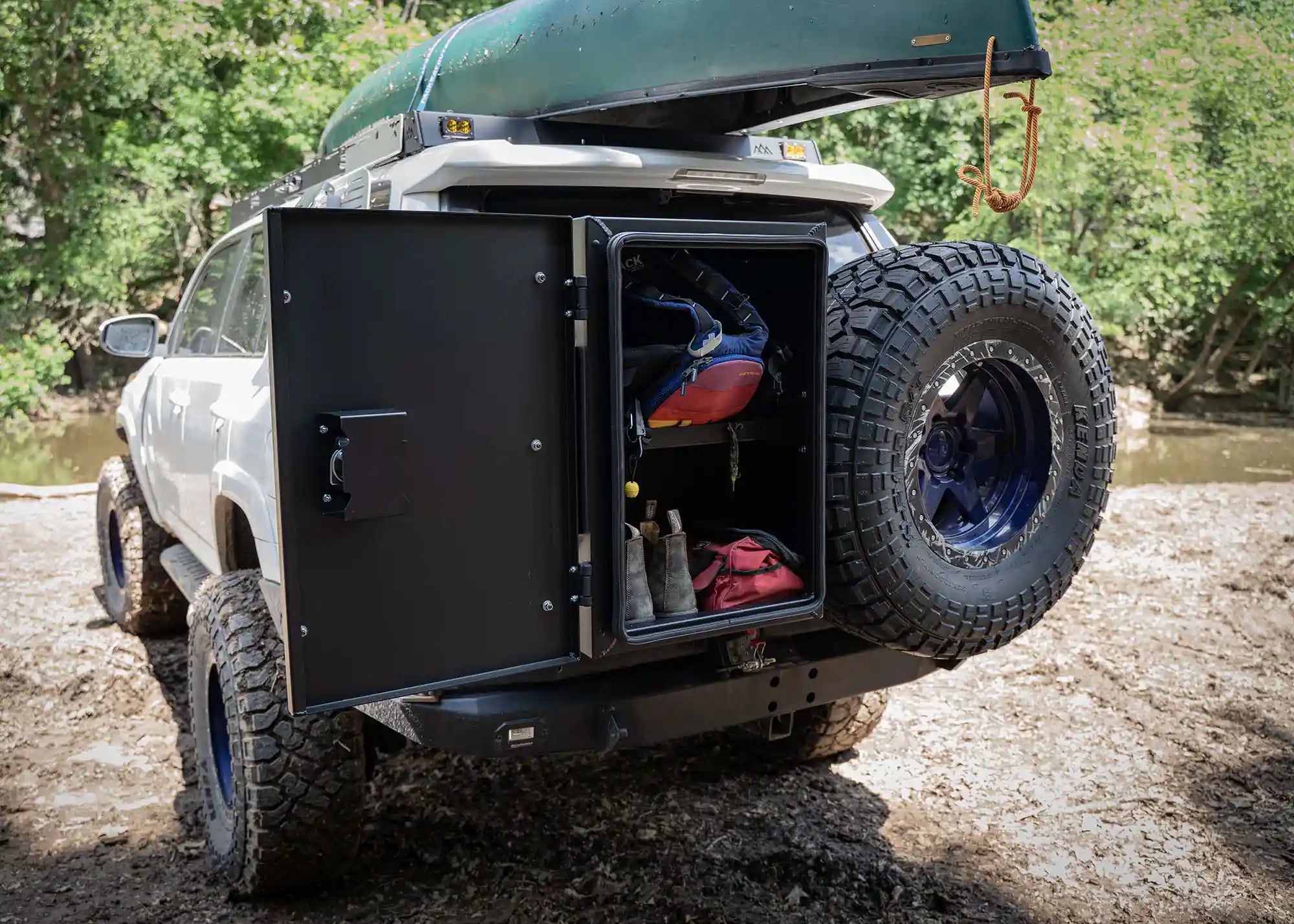 White Toyota 4Runner with Backwoods Adventure Mods Overland Storage Box mounted to the rear bumper housing water sports equipment organized by the interior shelving in the storage box.