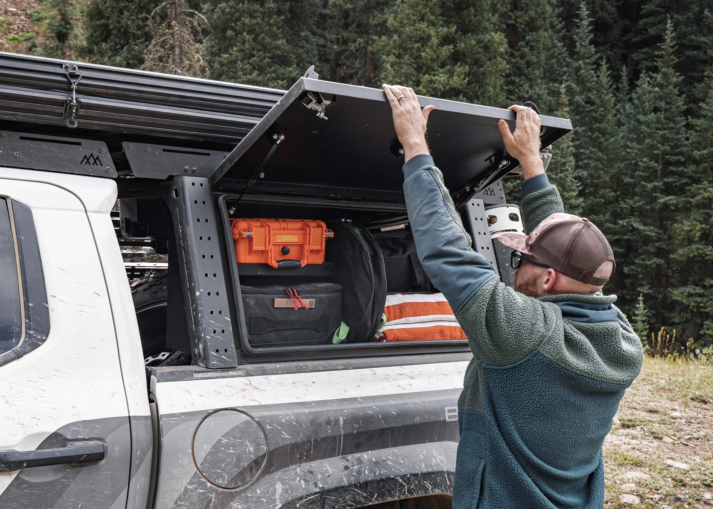 Man opening the Backwoods Adventure Mods Toyota Tacoma Overland Bed Rack optional cargo storage box