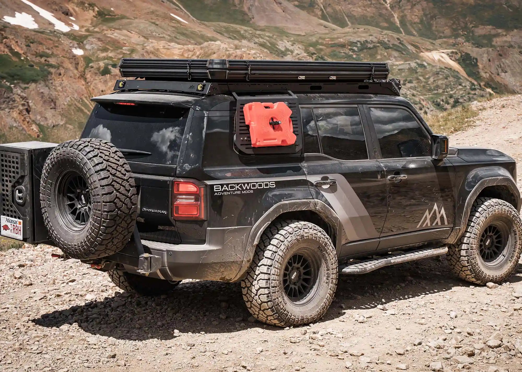 Toyota Land Cruiser 250 driving off road with a Backwoods Adventure Mods DRIFTR LC250 roof rack installed and roof top tent mounted on top