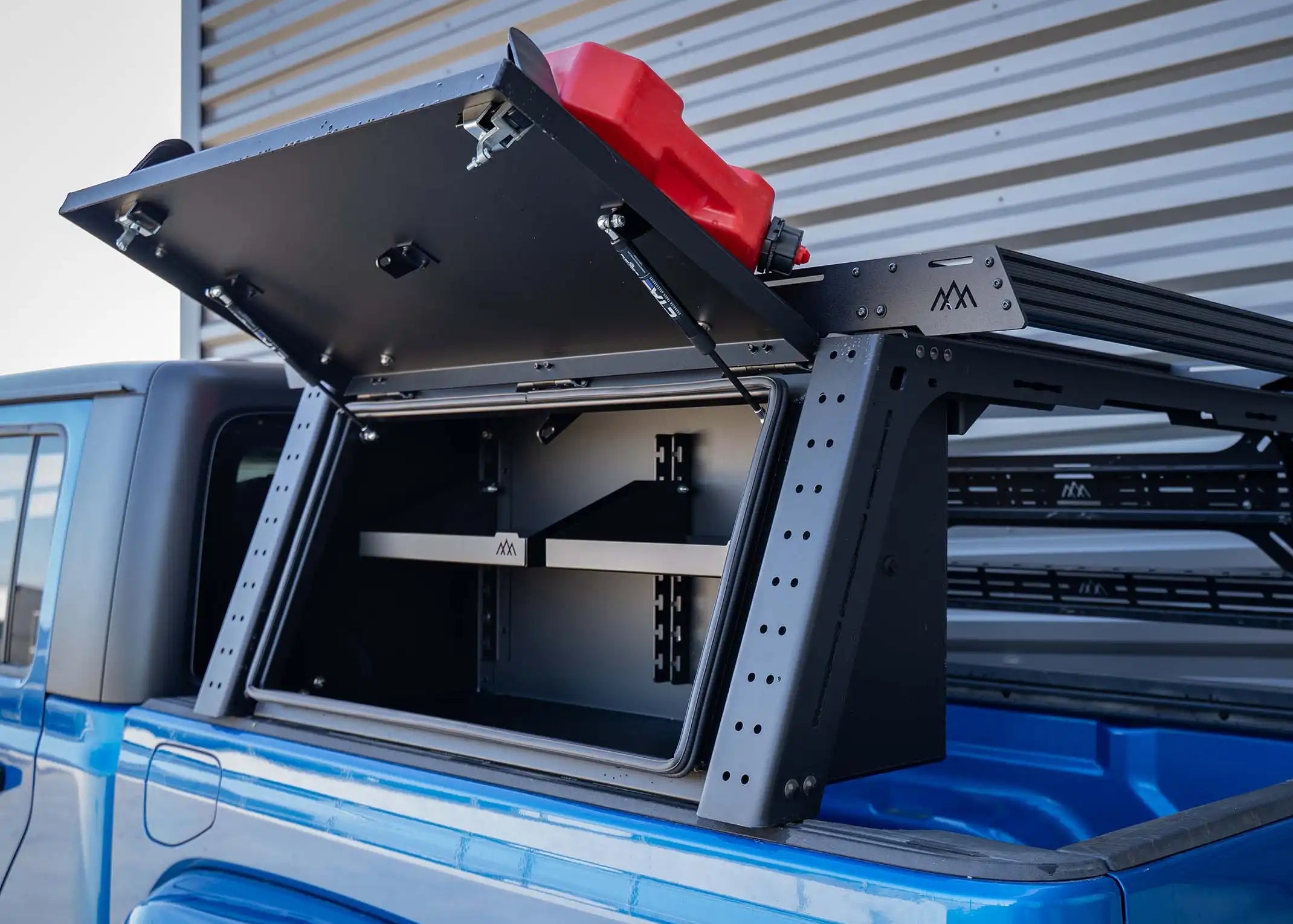 Backwoods Adventure Mods Jeep Gladiator Bed Rack with Overland Storage Box installed and lid open showing interior adjustable shelving