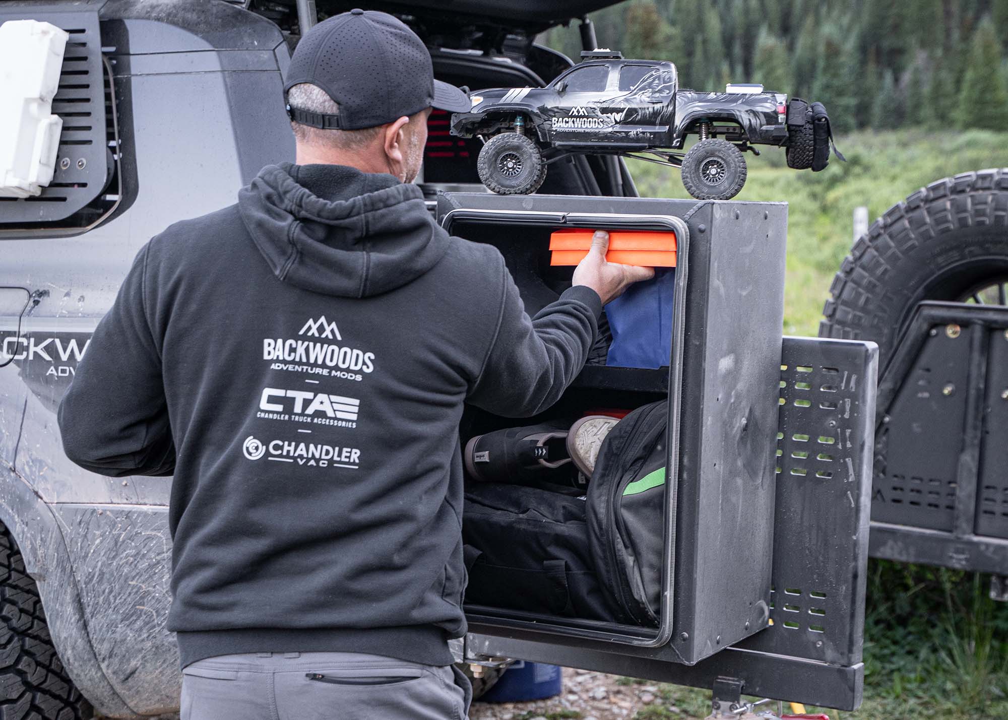 Man removing gear from the Backwoods Adventure Mods Universal off-road vehicle overland storage cargo box while camping