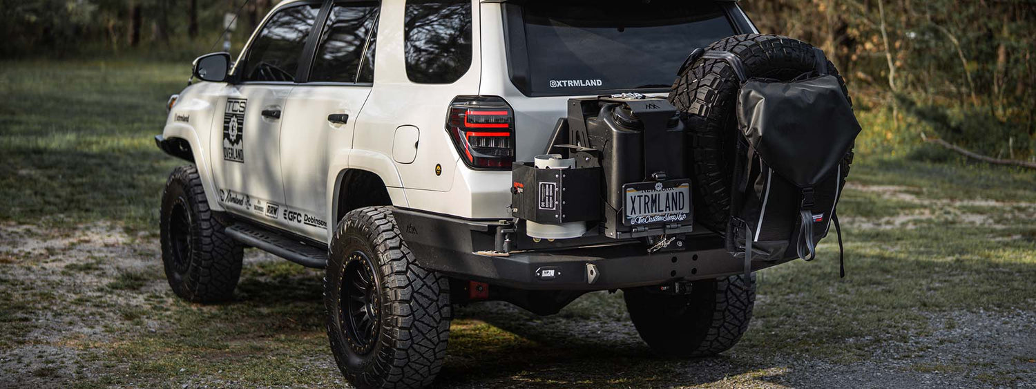 A toyota 4runner built for overlanding and offroading with a backwoods adventure mods dual jerry can holder on the rear bumper.