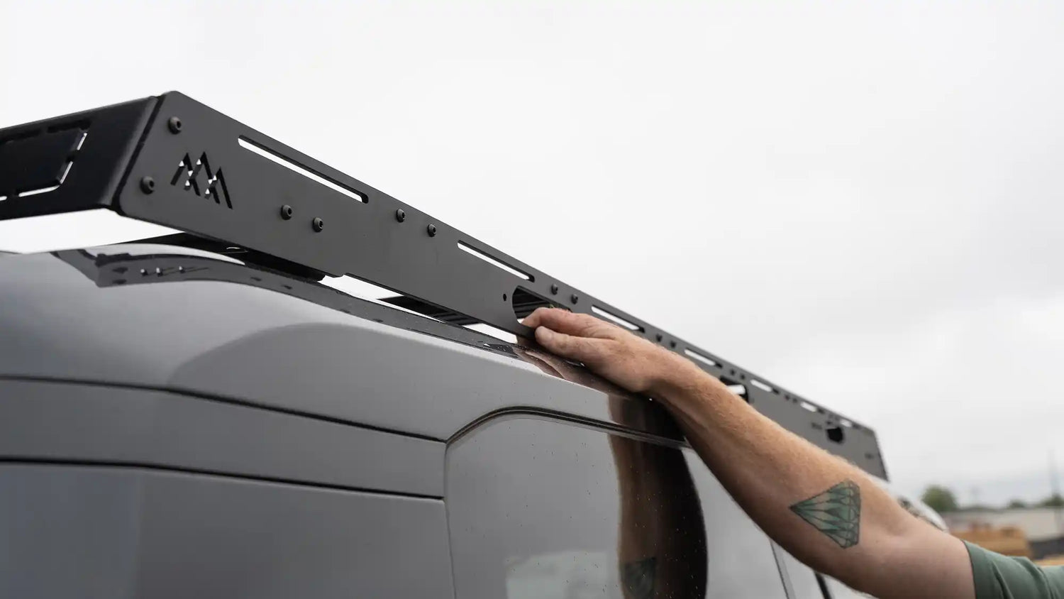 Man reaching up to mount cargo on a Lexus GX550 roof rack from Backwoods Adventure Mods