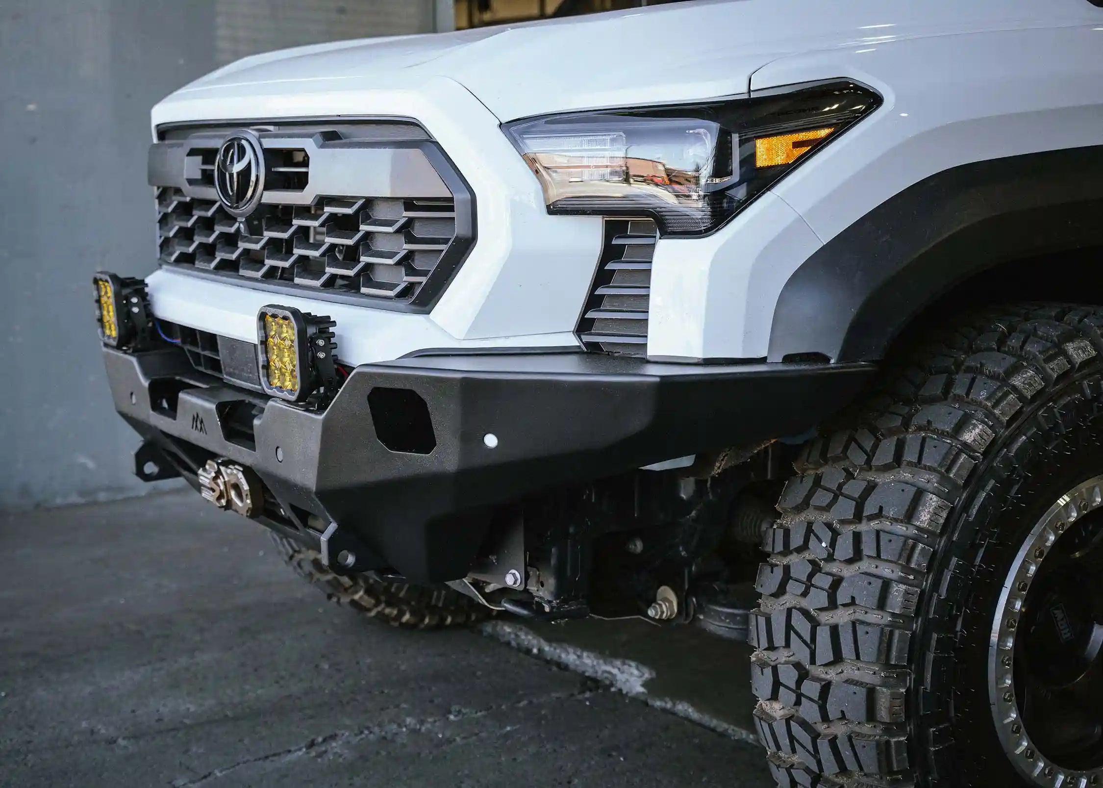 Installed side view of the Backwoods Adventure Mods Hi-Lite Overland Front Bumper on a 2024 Toyota Tacoma with off road driving lights