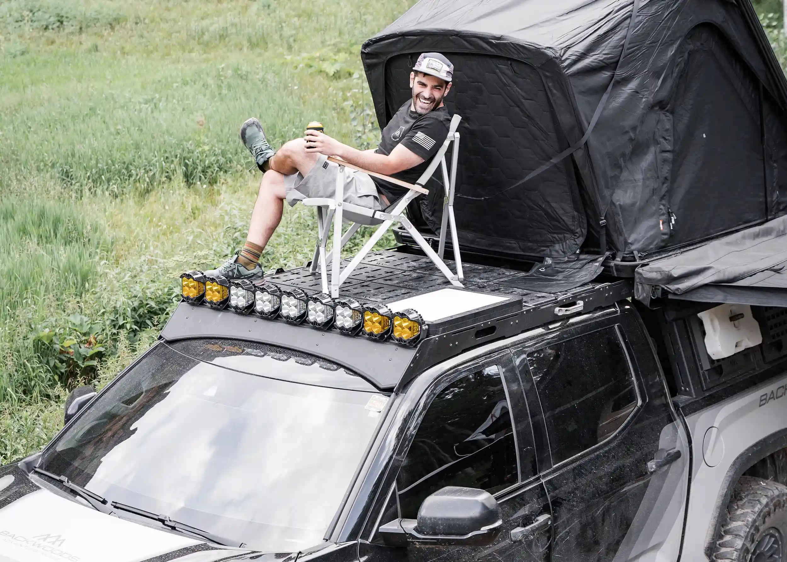 Man sitting in a camp chair on top of a Backwoods Adventure Mods DRIFTR roof rack installed on a 3rd Gen Toyota Tundra