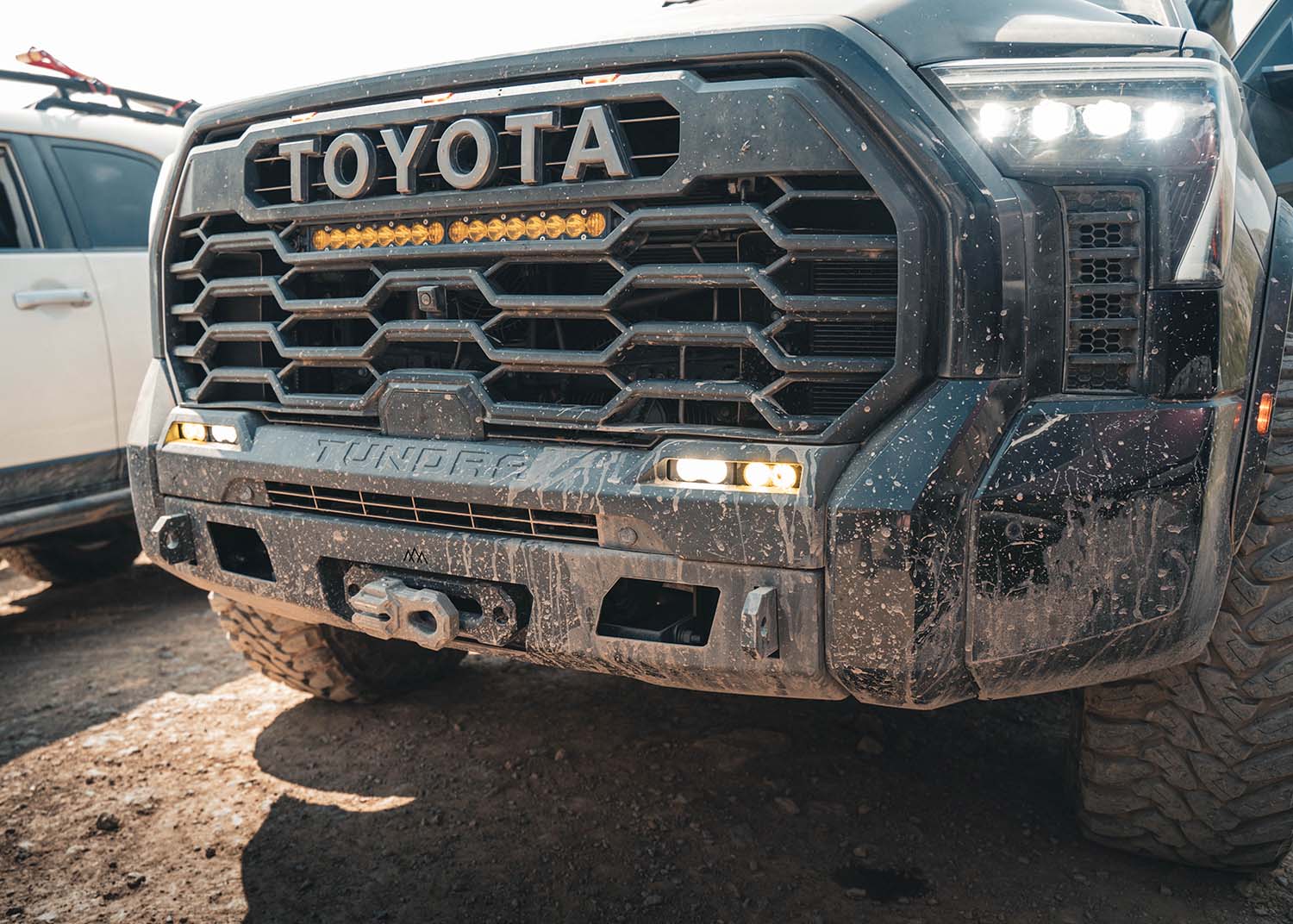 Close-up of the Backwoods Adventure Mods 2022 2023 2024 2025 3rd Gen Tundra Front Bumper covered in mud after driving off road
