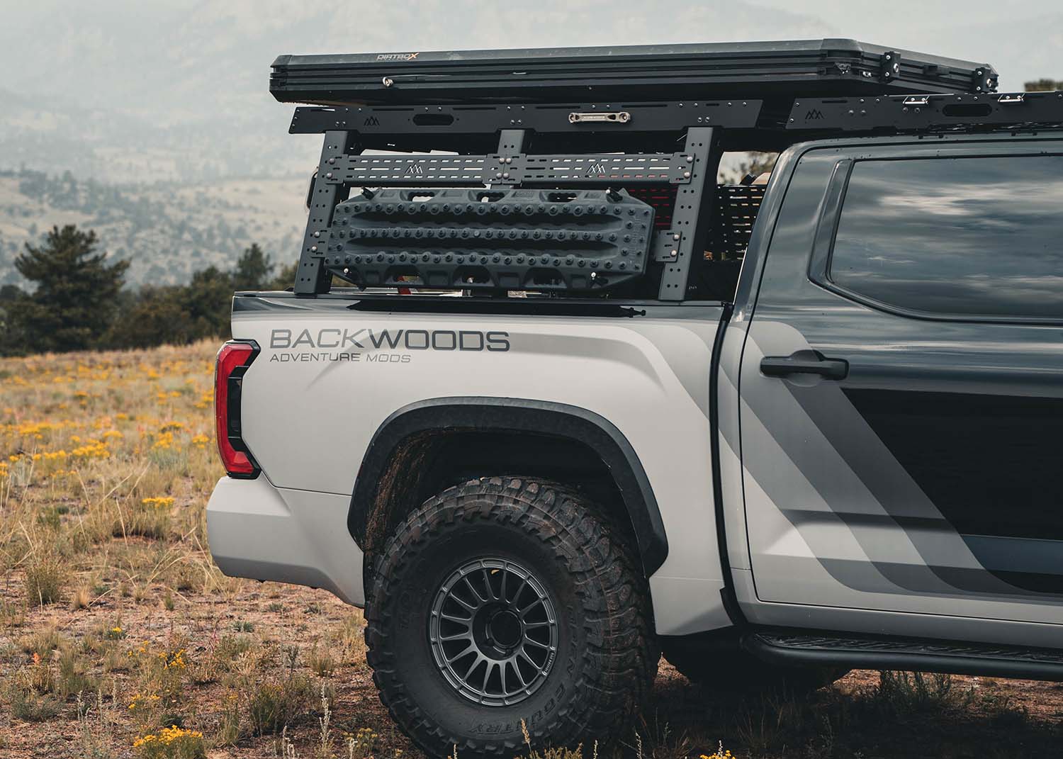White 3rd gen Tundra with a Backwoods Adventure Mods Full Height Toyota Tundra Truck Bed Rack installed with a roof top tent and off road traction boards mounted