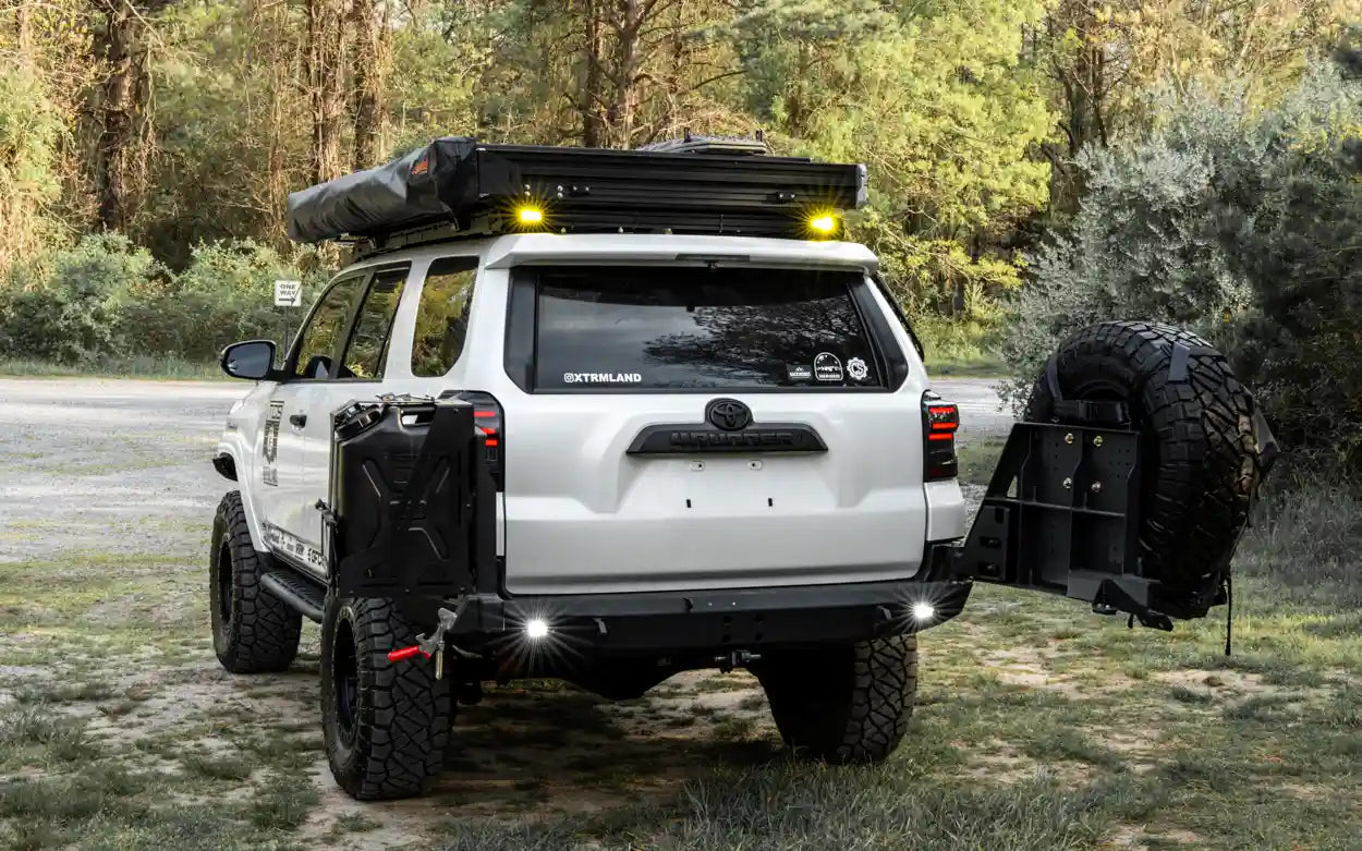 White 5th Gen Toyota 4Runner with  Backwoods Adventure Mods High Clearance Dual Swing Out Rear Bumper open while camping
