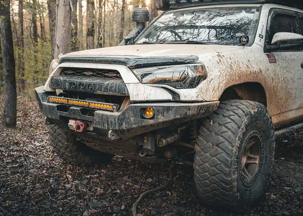 Backwoods Adventure Mods 5th Gen Toyota 4Runner Hi-Lite Overland Front Winch Bumper installed on a white 4runner and being used while off roading