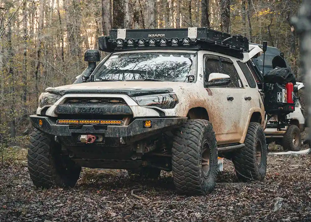 Backwoods Adventure Mods 2014-2022 5th Gen Toyota 4Runner Hi-Lite Overland Front Winch Bumper installed on a white 4runner driving off road covered in mud