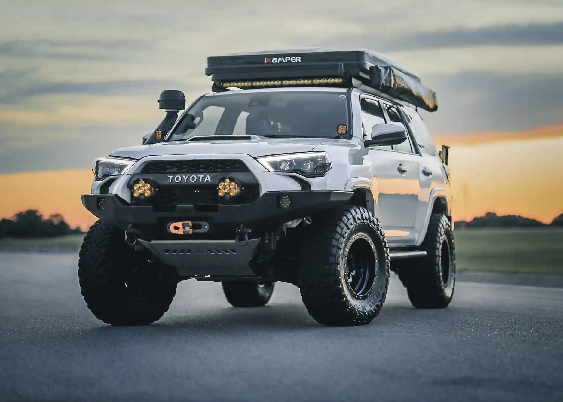 Backwoods Adventure Mods 2014-2022 5th Gen Toyota 4Runner Hi-Lite Overland Off Road Front Winch Bumper installed on a white 4runner with sunset in the background