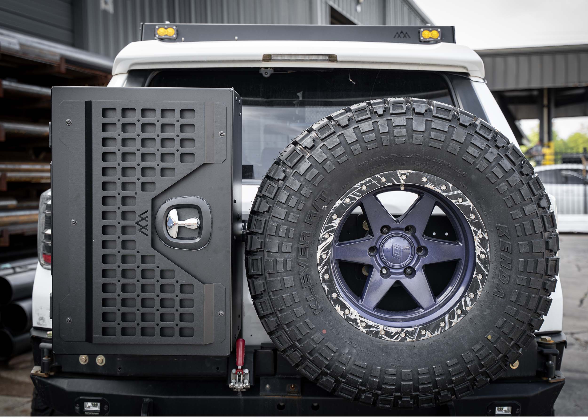 Back of a vehicle with a large tire and storage unit