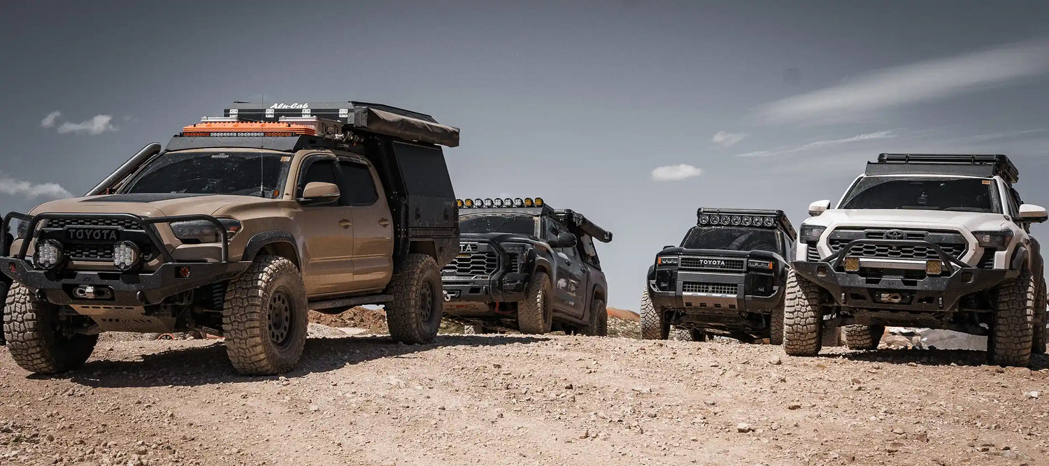 Group of Toyota Tacomas, Tundra, and Land Cruiser 250 outfitted with products from Backwoods Adventure Mods parked atop a mountain pass