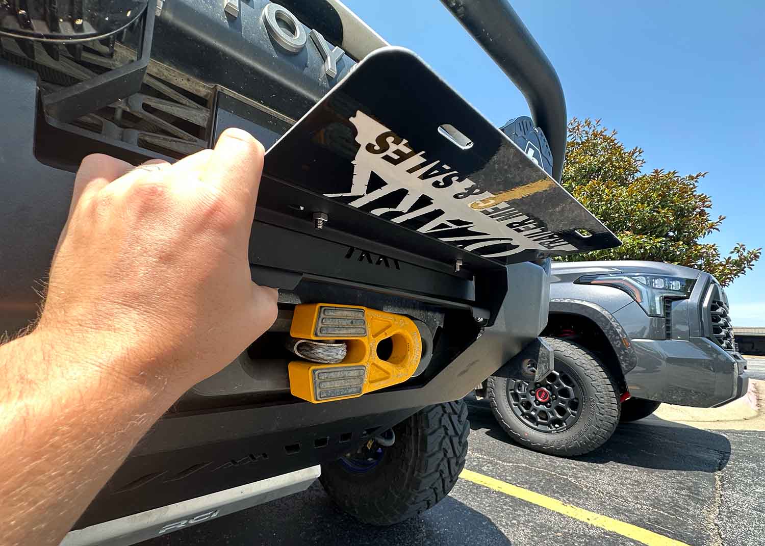 Lifting the flip up license plate bracket for Backwoods Adventure Mods Hi-Lite Series high clearance off road front bumpers to show hawse fairlead and winch
