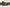 Person camping in an FSR Aspen Lite XL Rooftop Tent installed on a overland built Toyota Tacoma in a snow covered field with forest in the background | Backwoods Adventure Mods