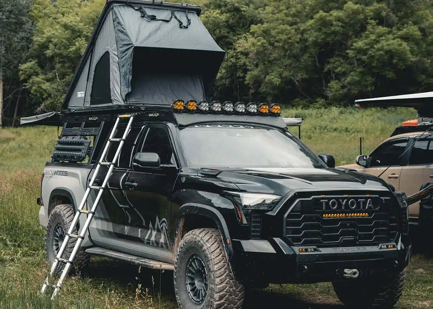 Roof top tent and off road accessories mounted to a Backwoods Adventure Mods Tundra truck bed rack and roof rack combo